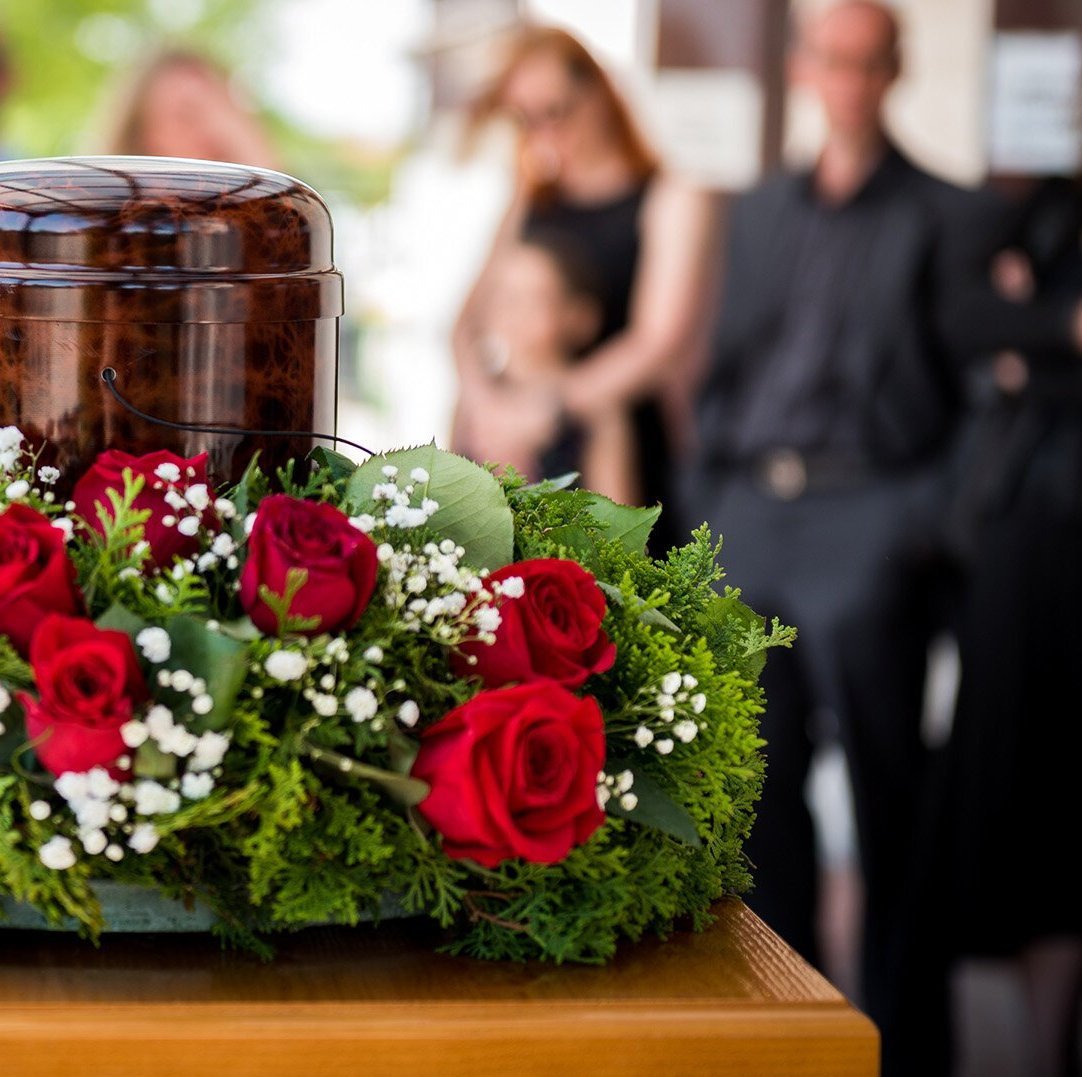 Urne mit Blumenkranz bei einer Trauerfeier